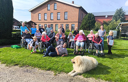 Gruppenfoto aller BewohnerInnen auf dem betriebswirtschaftlichen Hof, mit Bewohnerin Marta Reimers neben ihrer Enkelin und Uhrenkelkind, hat selber früher auf dem Hof gelebt
