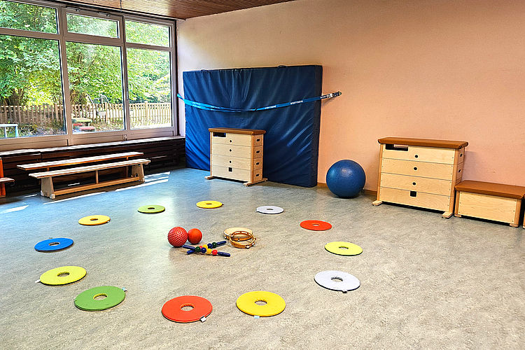 Bewegungsraum des Familienzentrums mit Sitzkreis, Weichboden und Turngeräten