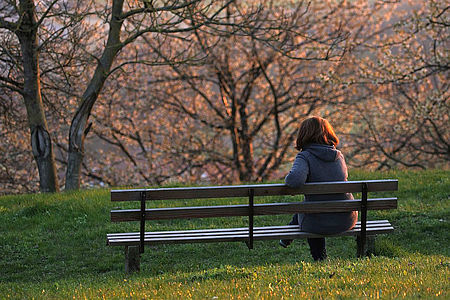 Einsame Mutter auf einer Parkbank im Winter