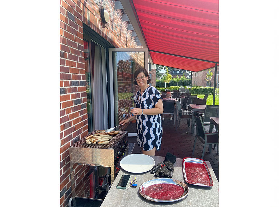 Dorit Bergzog steht lächelnd am Grill und brät Würstchen